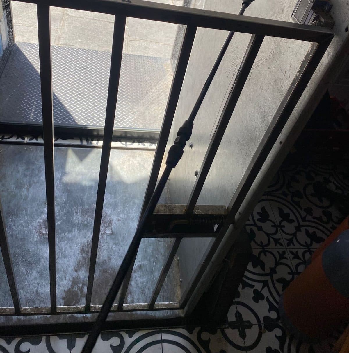 Lance de pulvérisation passée dans la grille du monte-charge d'un restaurant lors d'un traitement choc contre les cafards